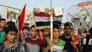 Protesters carry national flags and an electric fan in Baghdad, August 7, 2015. Photo by Karim Kadim/AP